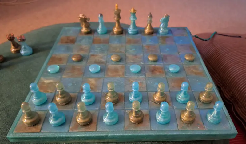 A epoxy resin chessboard in camouflage green and navy teal, lined up for a game of Proletarian Revolutionary Chess