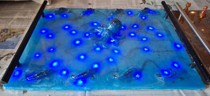 An epoxy resin tray, in ocean blue, with decorative octopus and fish and embedded LED lights
