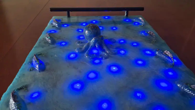 An epoxy resin tray, in ocean blue, with decorative octopus and fish and embedded LED lights